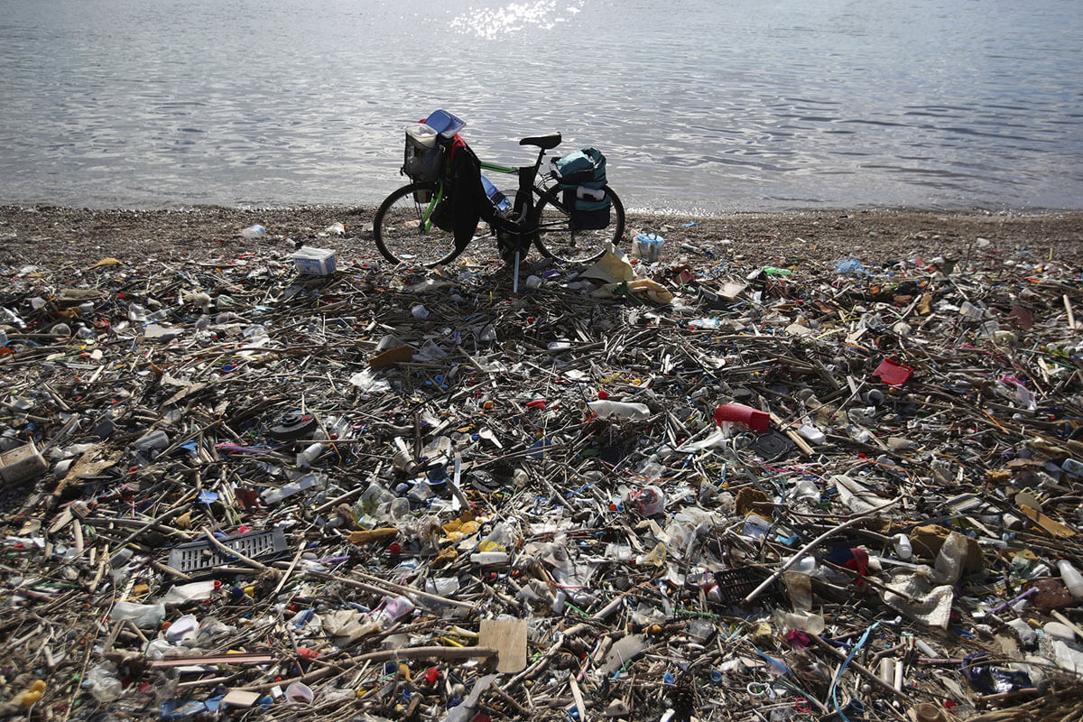 Sebuah sepeda yang diparkir di samping plastik dan sampah lainnya di pantai di Neo Faliro, Athena selatan, Yunani, 17 Januari 2018. Yunani memiliki garis pantai terpanjang di Eropa, dengan pengelolaan sampah yang buruk, dan penggunaan plastik sekali pakai yang parah dan mengotori dasar laut negara itu. Untuk mengatasi masalah ini, para relawan penyelam bekerja sebagai pengumpul sampah bawah air untuk membersihkan puing-puing — sebagian besar adalah plastik — yang mengotori dasar laut.