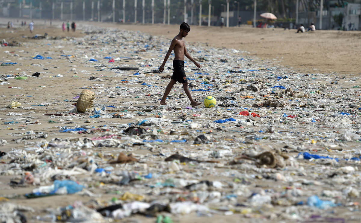 Seorang bocah India berjalan melewati sampah plastik di pantai Juhu di Mumbai, India, 2 Juni 2018