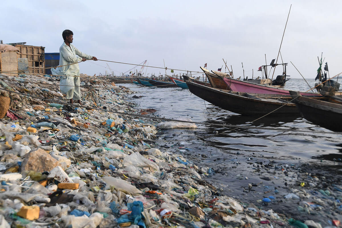 Seorang nelayan Pakistan menarik perahunya di antara sampah dan kantong plastik di pelabuhan di Karachi, Pakistan, 10 Mei 2018